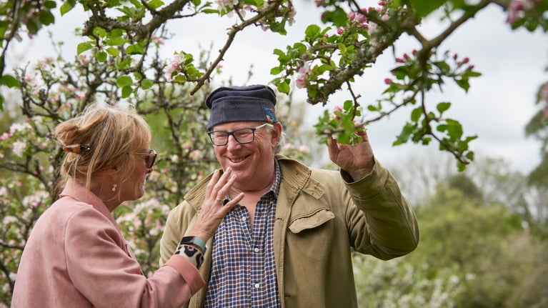 Two people stood under a tree looking at the blossom